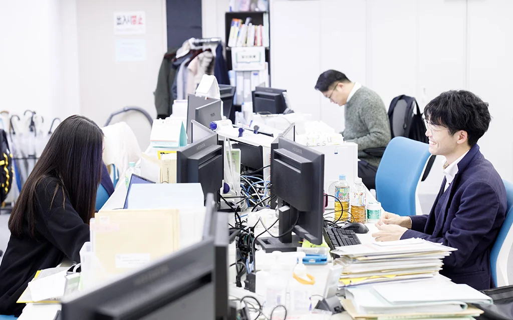 税理士法人Light UPの実際のオフィスで、スタッフ同士が会話しながら作業している様子